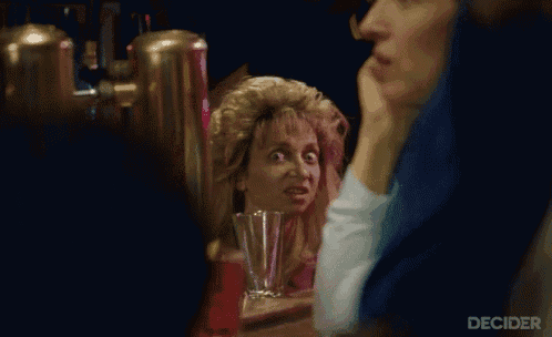 a woman sitting at a table with a drink in her hand and the word decider on the bottom left