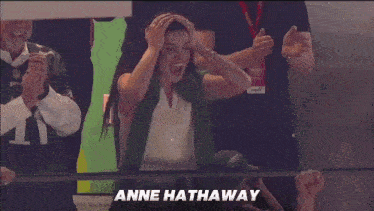a woman in a green scarf is screaming with the name anne hathaway written above her