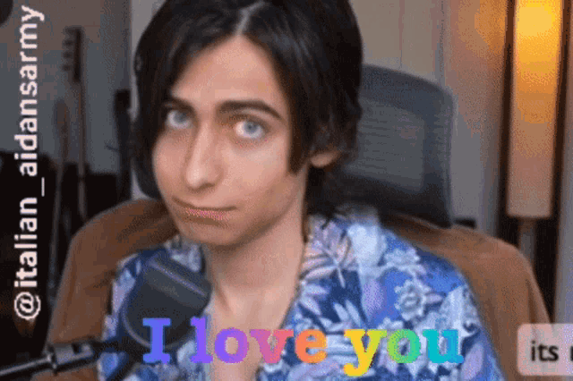 a young man sitting in front of a microphone with the words i love you on the bottom
