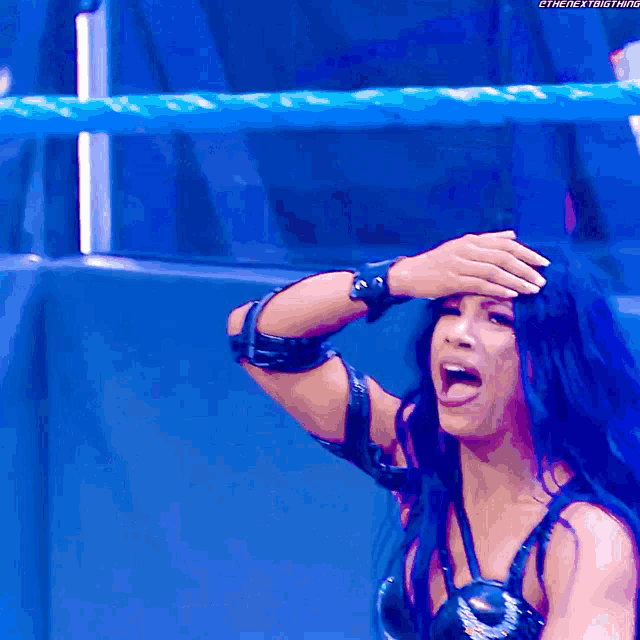 a woman in a wrestling ring covering her forehead with her hand while screaming