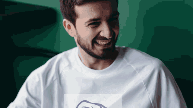 a man with a beard is wearing a white t-shirt with a picture of a hand on it