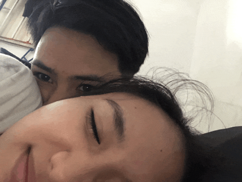 a man and a woman are laying on a bed and the woman is sleeping
