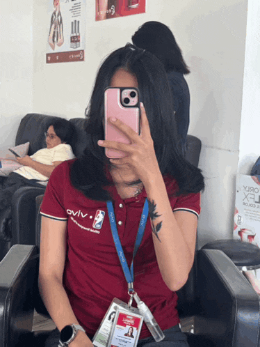 a woman is taking a picture of herself with her phone while wearing a shirt that says oviv on it