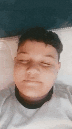 a young boy is laying on a bed with his eyes closed