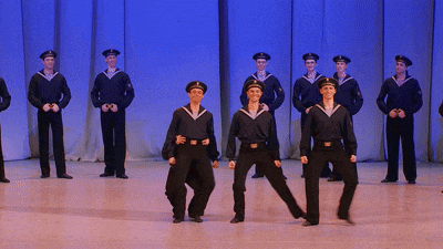 a group of men in navy uniforms are dancing on stage