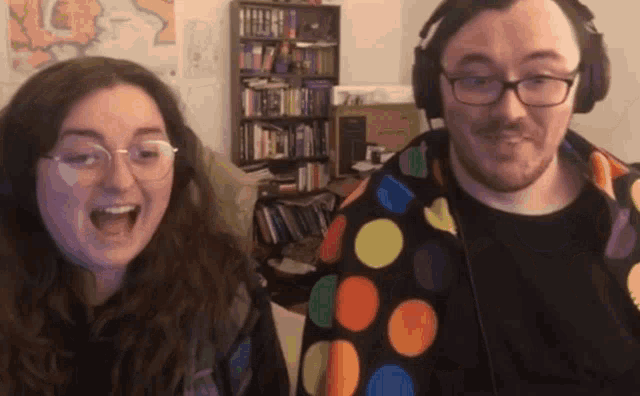a man wearing headphones and a woman wearing glasses are laughing together
