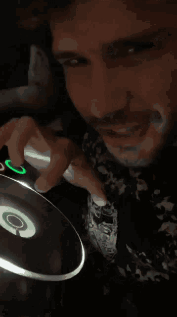 a man with a mustache is playing a cd with a green button