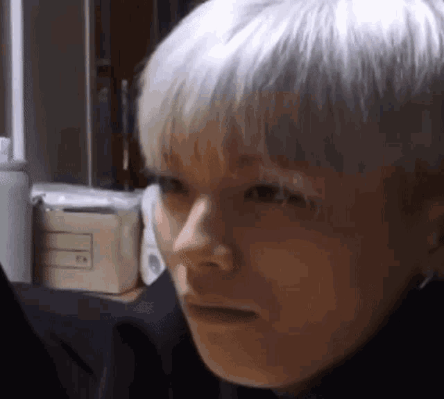 a close up of a person 's face with white hair making a face .