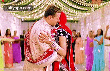 a man is holding a woman in his arms while they dance at a wedding reception .