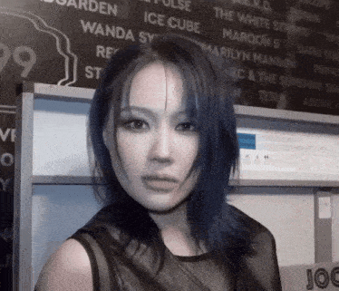 a woman with blue hair is standing in front of a blackboard with the number 99 on it