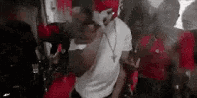 a man in a white shirt is dancing in front of a crowd of people .