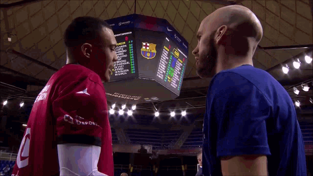 two men are standing in front of a scoreboard that says barcelona