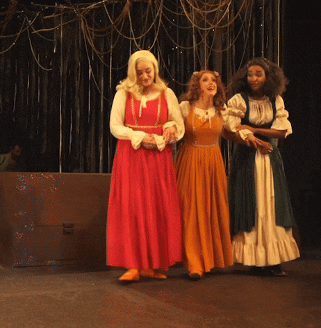 a woman in a red dress stands between two other women