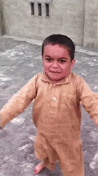 a young boy in a tan shirt is smiling and walking