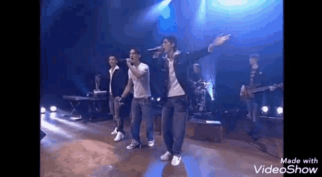 a group of people are standing on a stage holding microphones .