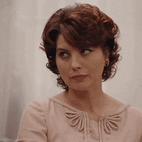 a woman wearing a pink shirt and earrings is looking to the side