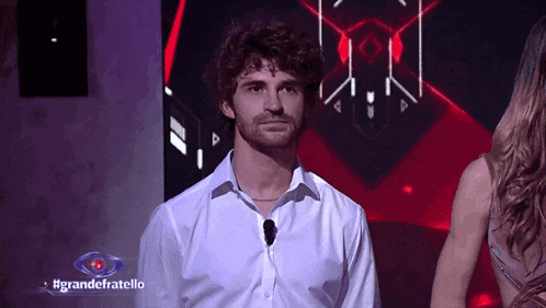 a man in a white shirt is standing in front of a sign that says grande fratello