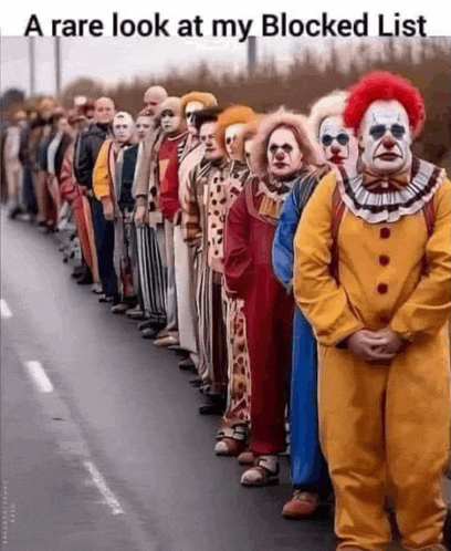 a row of clowns are standing next to each other on the side of the road .