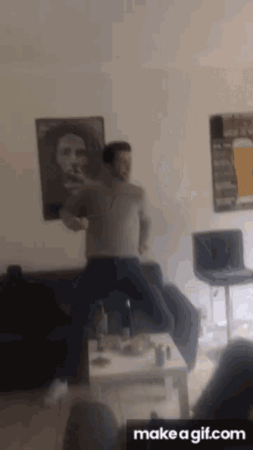 a man is jumping in the air in a living room with a make a gif.com button