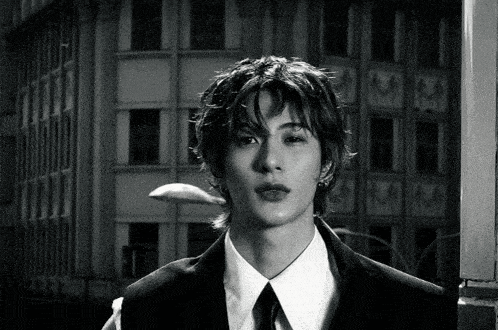 a young man in a suit and tie stands in front of a building