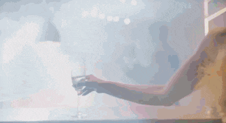 a woman in a yellow dress is holding a glass of wine in her hand .