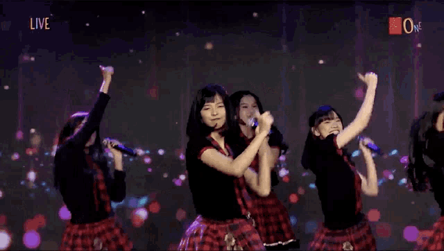 a girl singing into a microphone in front of a screen that says live on it