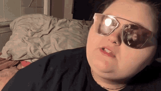 a woman wearing sunglasses and a black shirt is making a funny face