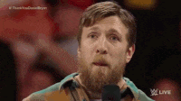 a man with a beard is standing in front of a microphone in a wrestling ring .