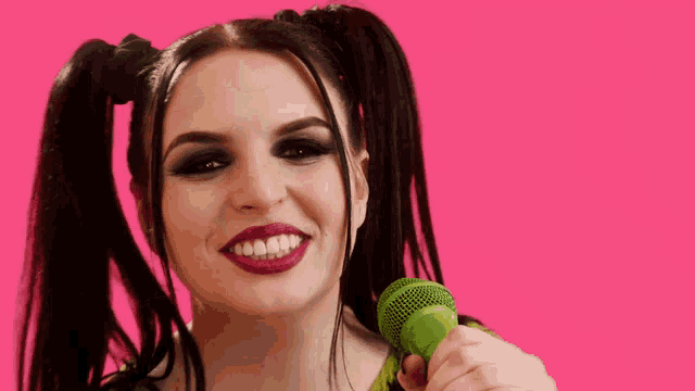 a woman with pigtails holds a green microphone
