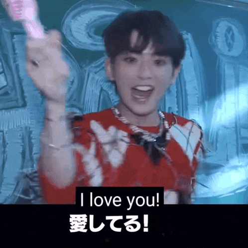 a man in a red shirt is holding a pink object and saying i love you