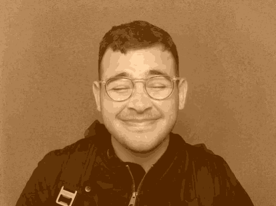 a man wearing glasses and a black jacket with the letter i on it