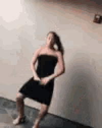 a woman in a black dress is standing on one leg .