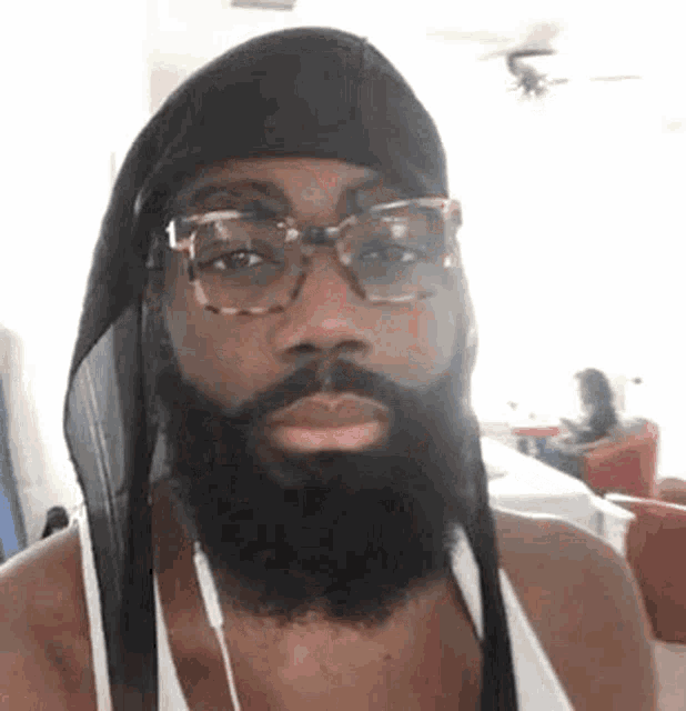 a man with a beard and glasses is wearing a headband and headphones .