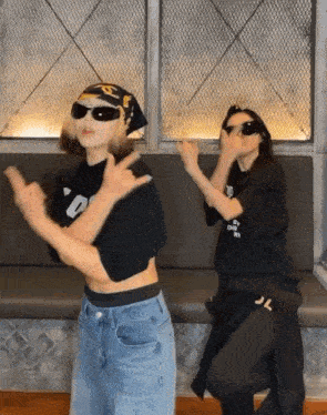 two women wearing sunglasses and a bandana are dancing in front of a couch .