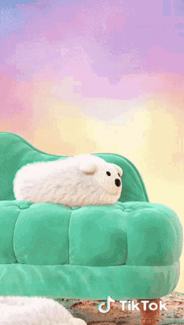 a stuffed animal laying on top of a green couch with a tiktok logo in the corner