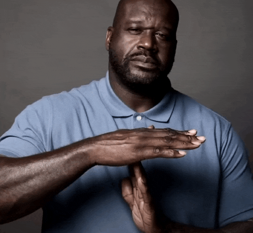 a man in a blue shirt holds his hands together in front of his face