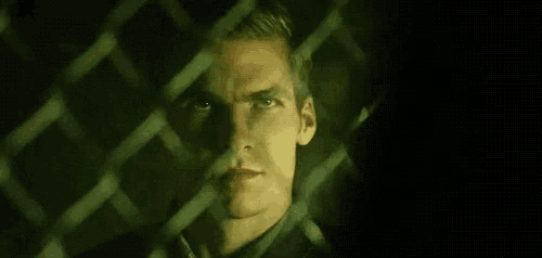 a close up of a man behind a chain link fence .