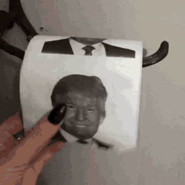 a woman is holding a roll of toilet paper with donald trump 's face on it .