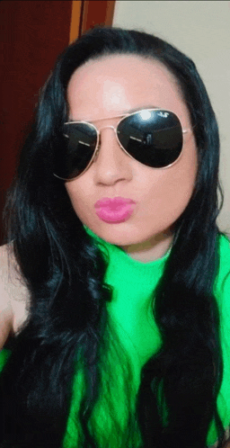 a woman wearing sunglasses and a green sweater