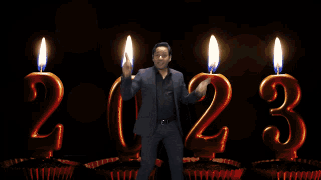 a man stands in front of candles that spell out the year 2023
