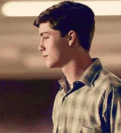 a young man in a plaid shirt is looking down at something .