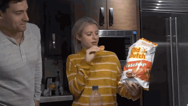 a woman holds a bag of old dutch ketchup chips in her hand
