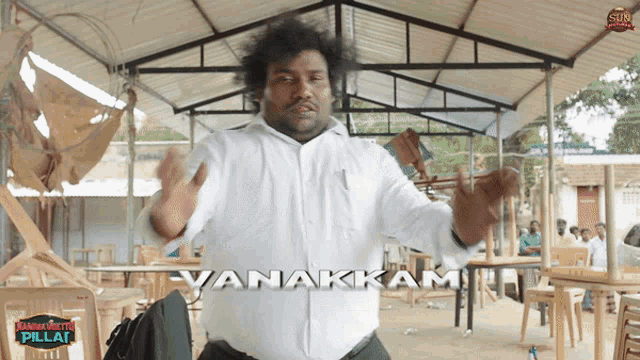 a man in a white shirt is standing in front of tables and chairs and the word vanakkam is on the bottom
