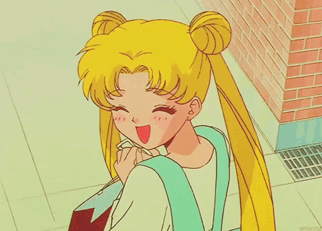 a girl with buns on her hair is smiling in front of a pink brick wall