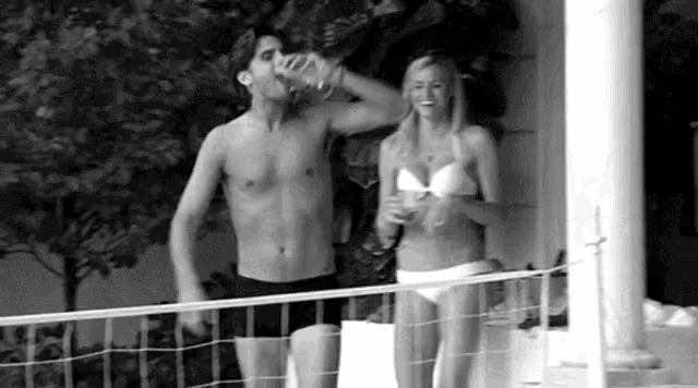 a man and a woman in bikinis are standing next to each other on a porch .