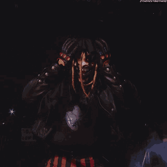 a person with dreadlocks is wearing a black jacket and red and white striped pants