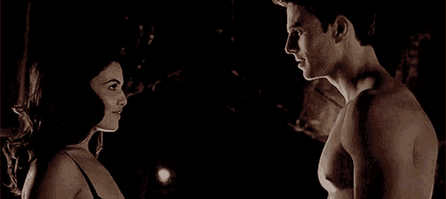 a man and a woman are standing next to each other in the dark looking at each other .