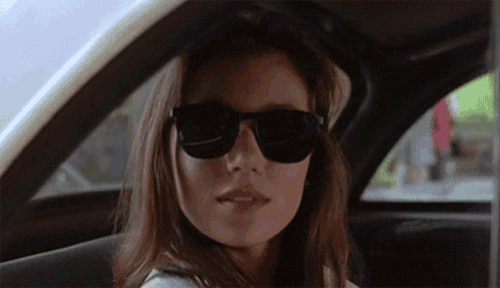 a woman wearing sunglasses is sitting in a car looking out the window .