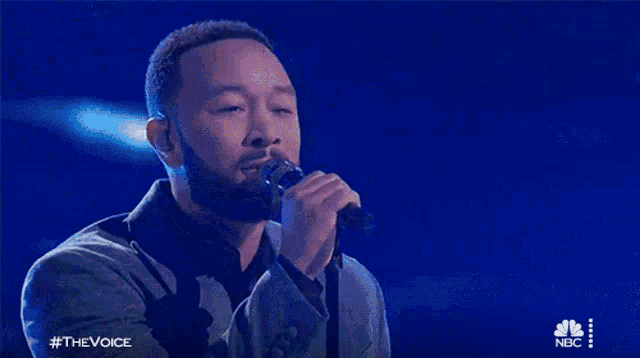 a man singing into a microphone with #thevoice on the bottom right