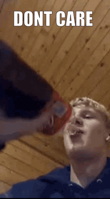 a man drinking from a coca cola bottle with the words " dont care " on the bottom